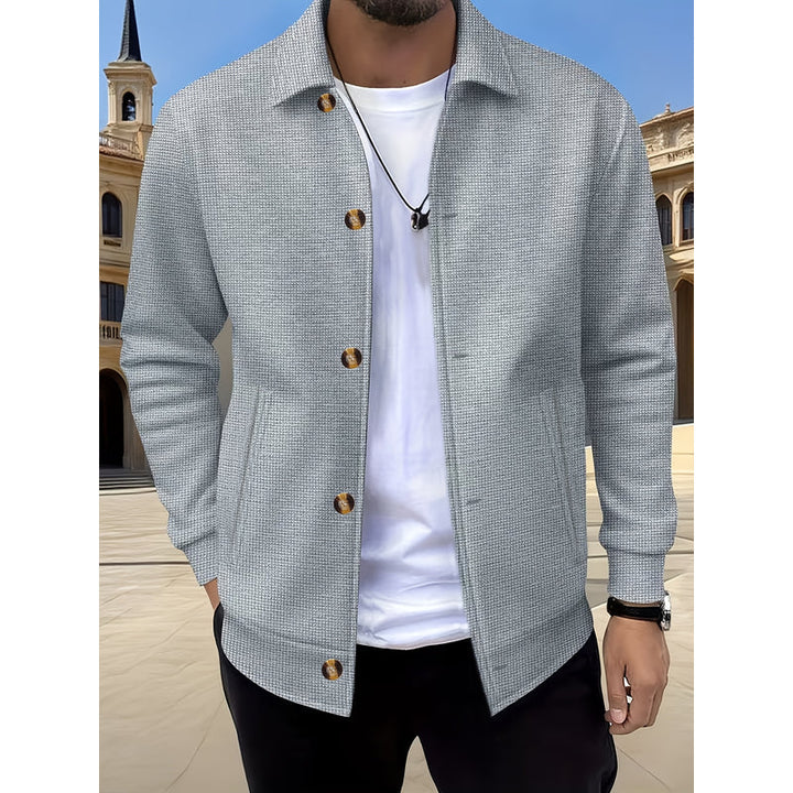 Uomo con giacca grigio aperta su t-shirt bianca