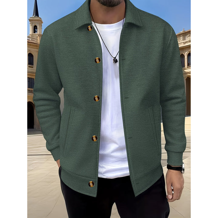 Uomo con giacca verde militare aperta su t-shirt bianca