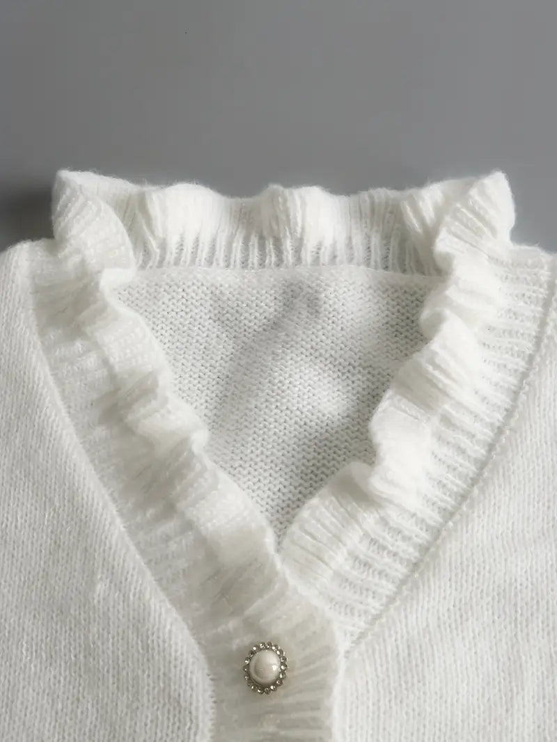 Dettaglio dei bottoni decorativi del maglione bianco