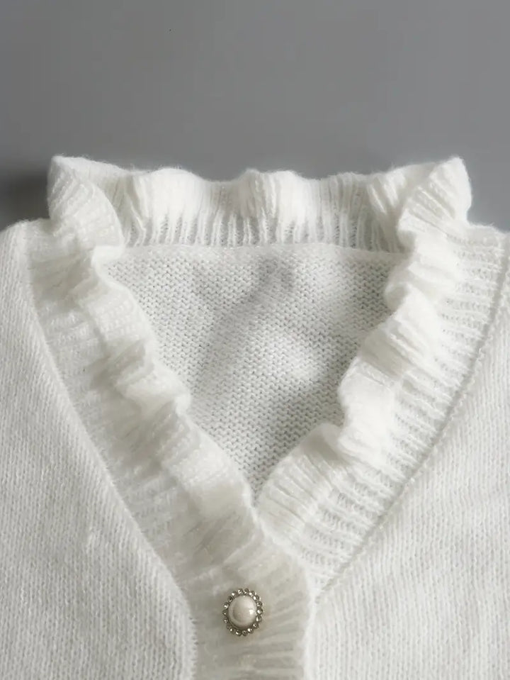 Dettaglio dei bottoni decorativi del maglione bianco