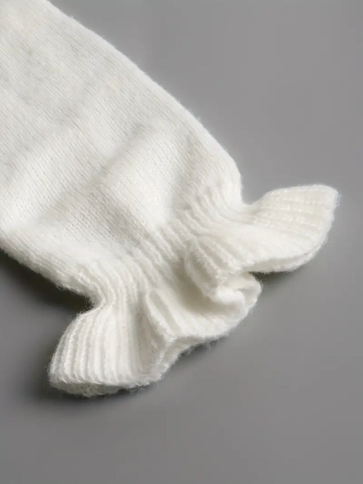 Dettaglio del polsino ondulato del maglione bianco